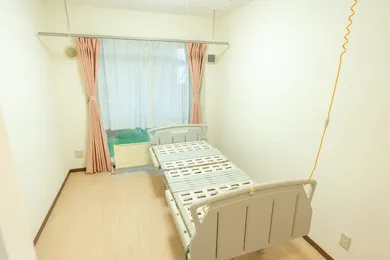 介護施設の居室。ベッドと窓、カーテンが備えられた個室